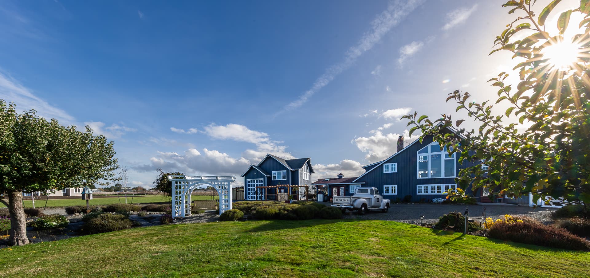 A picturesque blue house surrounded by greenery and a bright sky.
