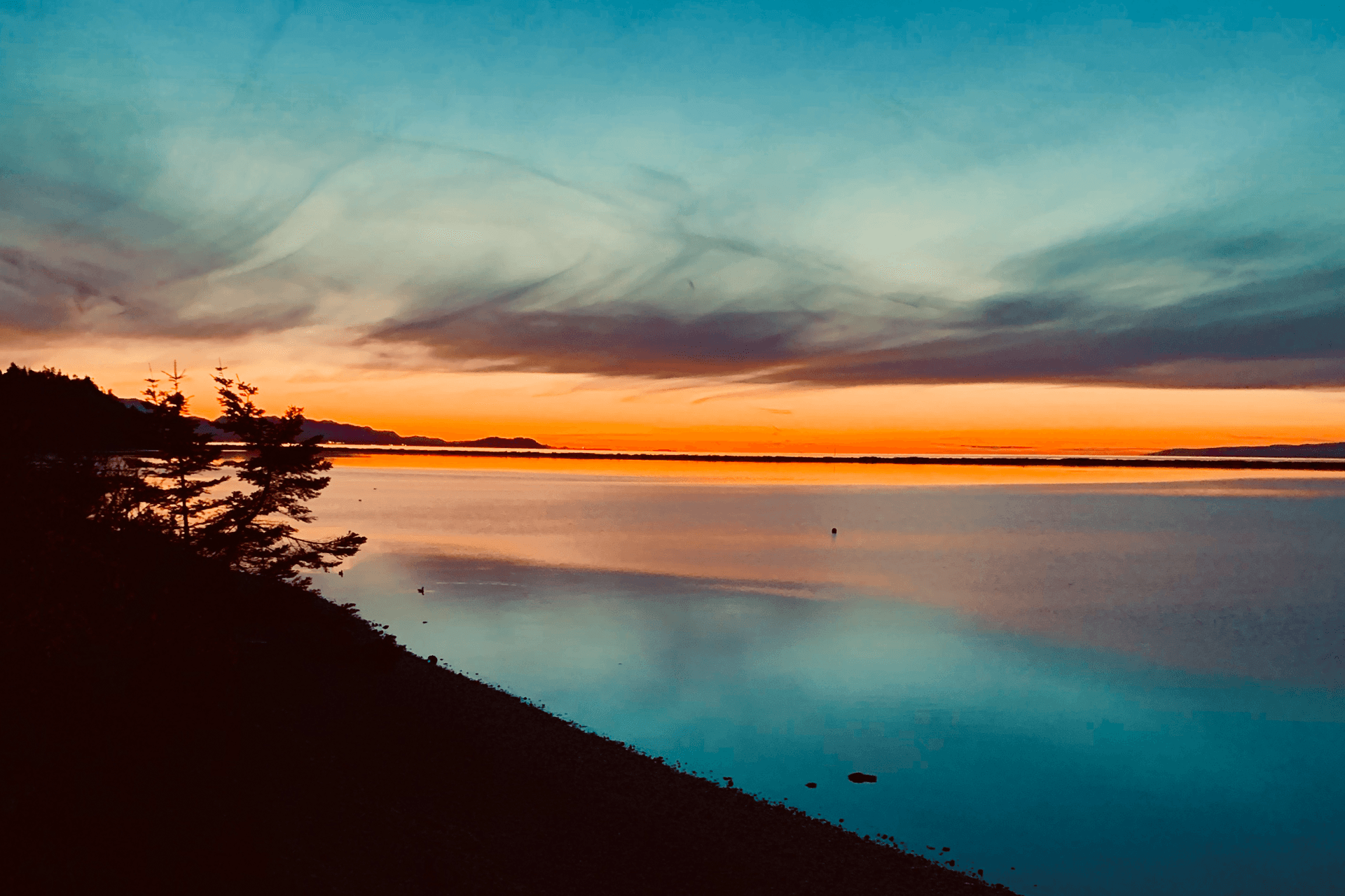 A serene lake at sunset, reflecting vibrant orange and blue hues.